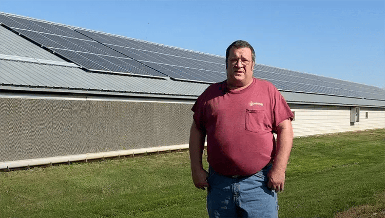 Lamar Martin is standing in front of his poultry house with solar panels.